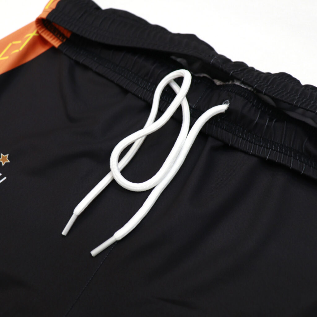 White drawstring and waistband detail on black volleyball shorts