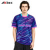 Model facing forward in a purple shirt with cyan and pink diagonal stripes, lettering and sleeve trim.